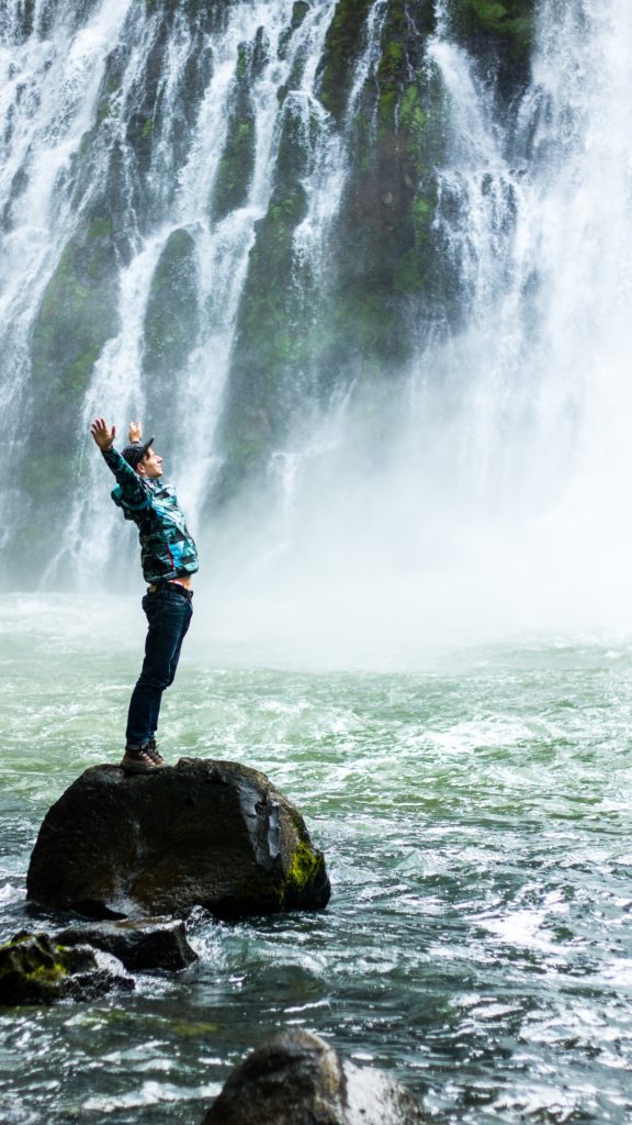 Mann vor einem Wasserfall Der Abenteurer